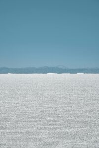 Expansive salt flat landscape with mountain backdrop in Jujuy, Argentina, under a clear blue sky.